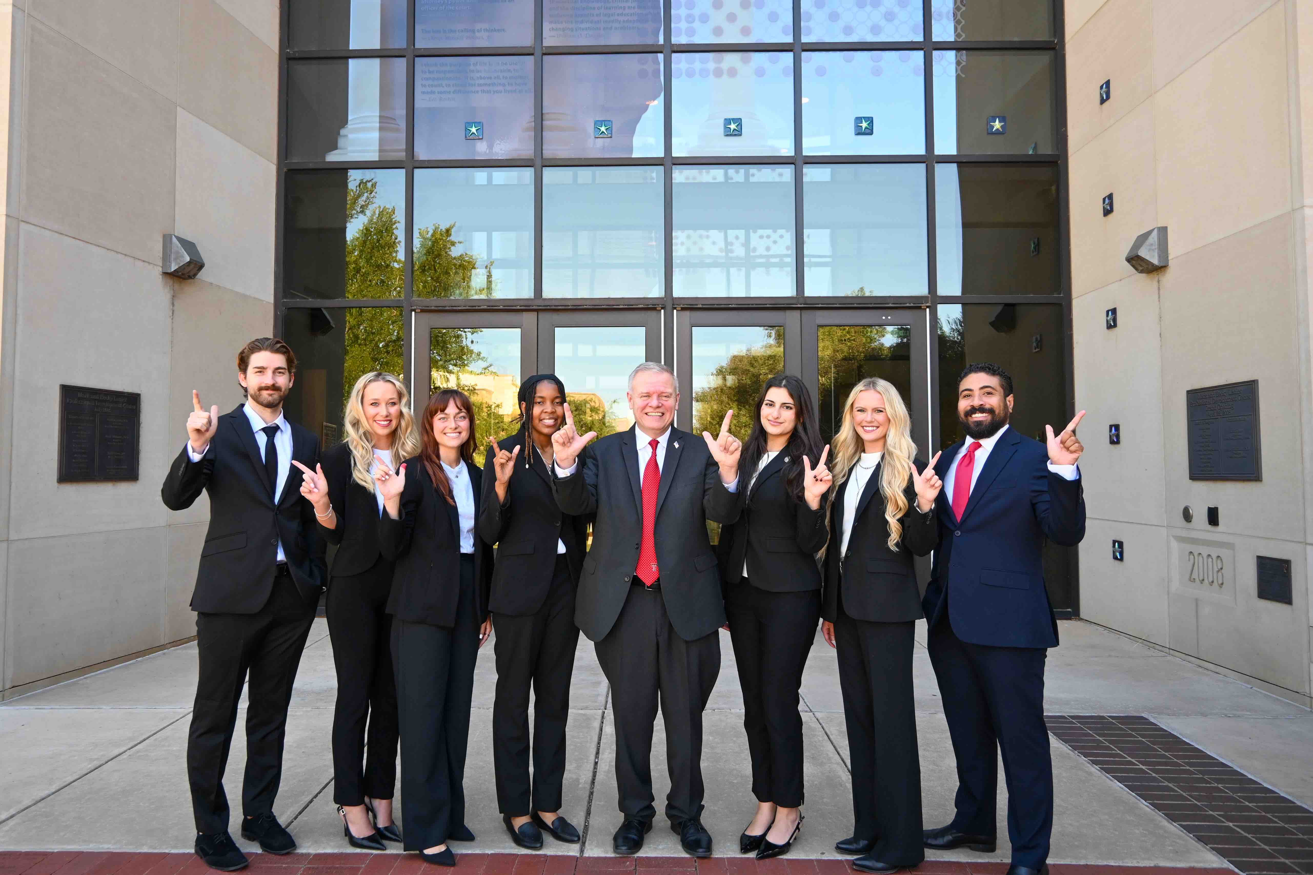 Group photo of Texas Tech Law Veterans Law Clinic students with Professor Mark “Max” Maxwell, all smiling outside the Lanier Professional Development Center. From left to right: Aaron Sharpe, Bailey Dietzmann, Faith Collins, Destiny Pemberton, Professor Maxwell, Sally Nasrawi, Lettie Morris, and Franklin Jones.
