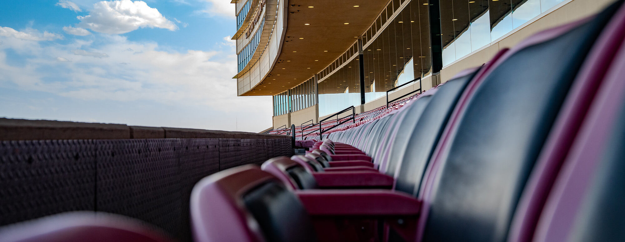 A view of a row of stadium seats in ATT Stadium looking up toward the blue sky