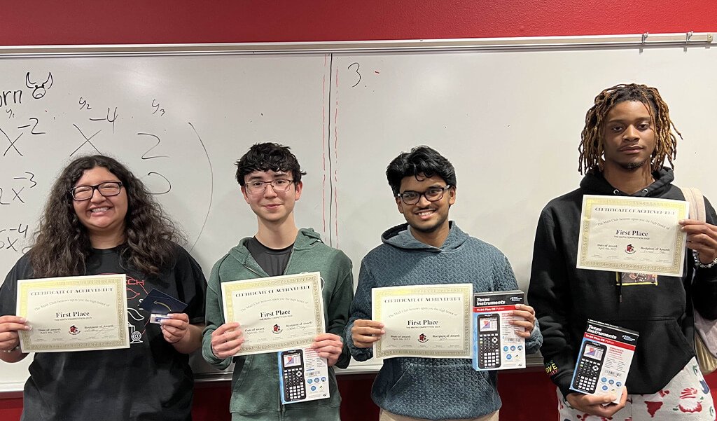 Four Math Club students receiving awards during a meeting