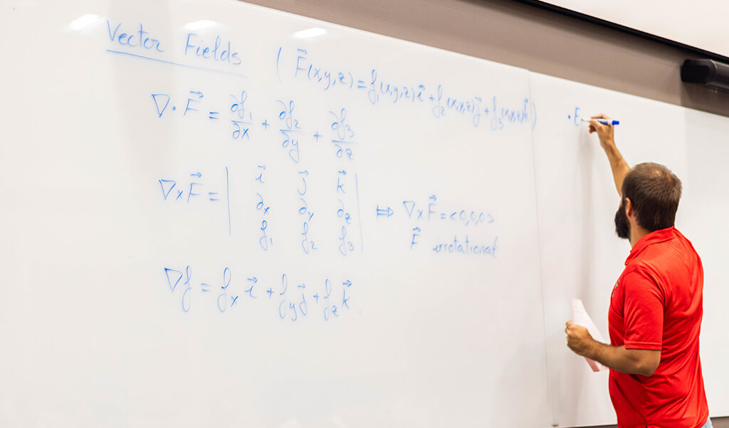 Dr. Pampano teaching in a classroom writing on a whiteboard
