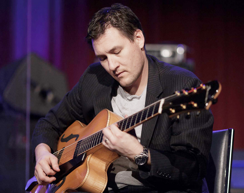 Man sitting on stage playing guitar