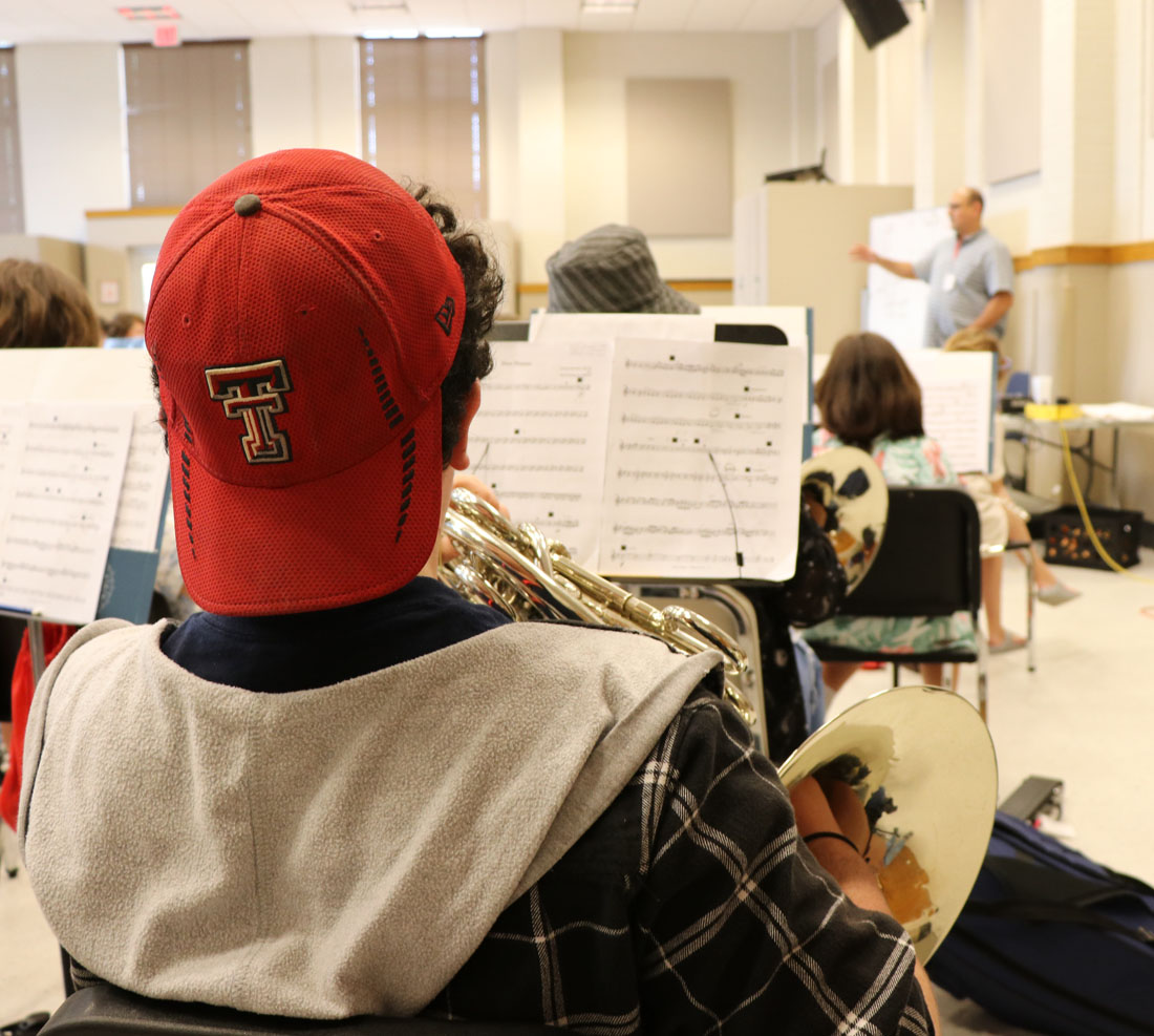 TTU summer band camp student playing sheet music holding french horn