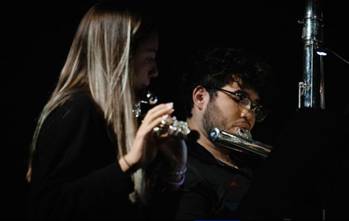 2 flute students performing in front of a microphone