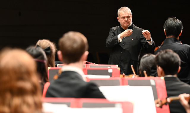 Faculty conductor in front of orchestra with violin solo