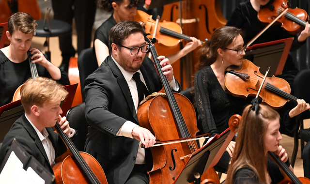 Students playing cellos in an orchestra