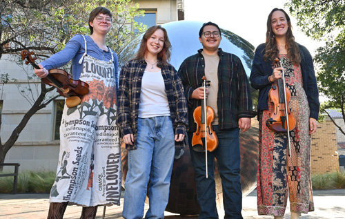 SOM Vernacular Tech Folk Fiddlers posing outside with their instruments
