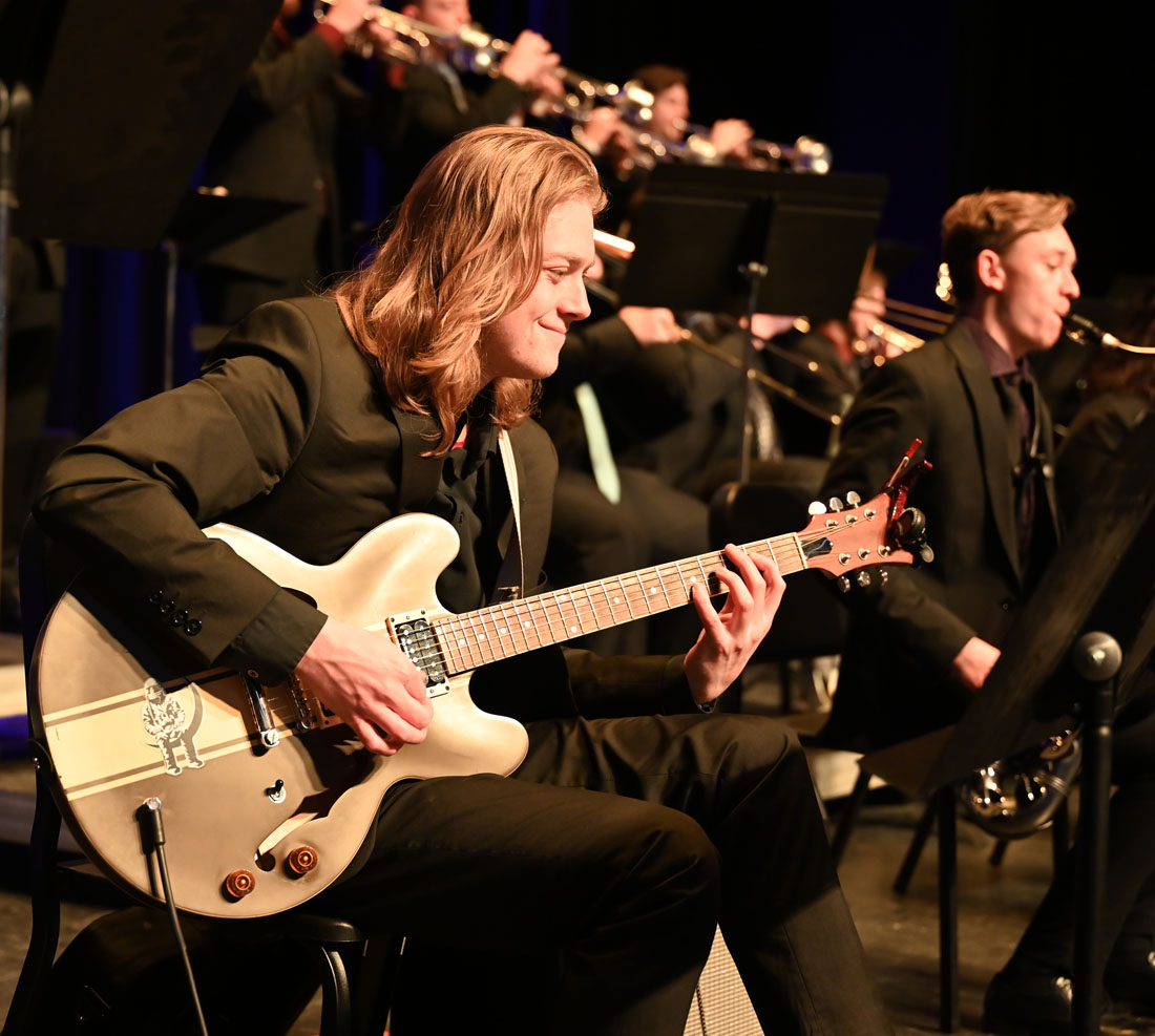 Student playing guitar on stage