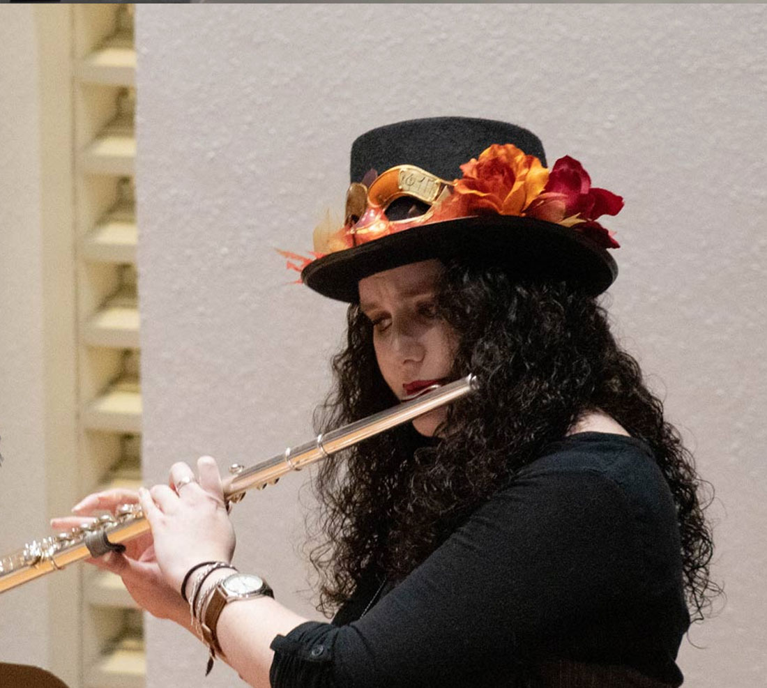 Student playing flute in costume with heavy makeup