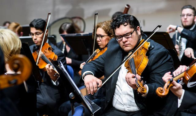 Violins playing to an orchestra