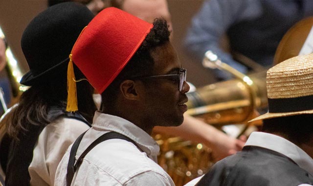 Student in rehearsal wearing a fez hat