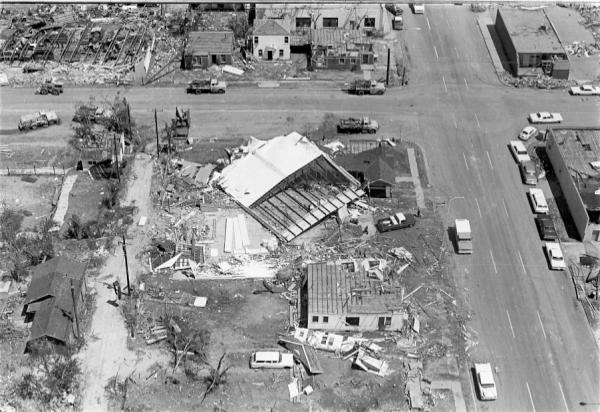 Overhead view of the tornado damage, trees are stripped of leaves, commerical and residential buildings are destoryed.