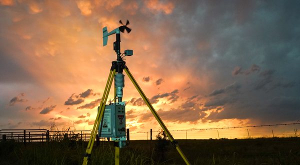StickNet rapid-deploy weather station on a tripod in a field at sunset