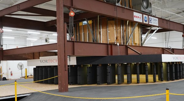 The VorTECH tornado simulator: a steel frame housing a ring of dark rotation vanes inside a laboratory building