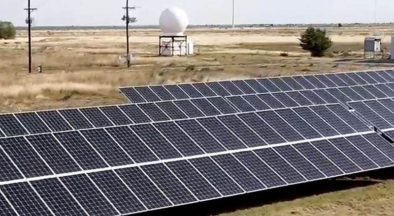 Solar array at the NWI field site with a radar radome and instrument towers on the horizon