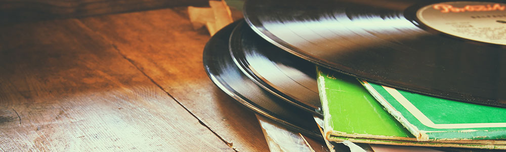 stack of vinyl records and worn sleeves on wood floor