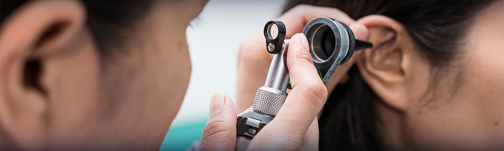 Doctor examining patient's ear with otoscope.