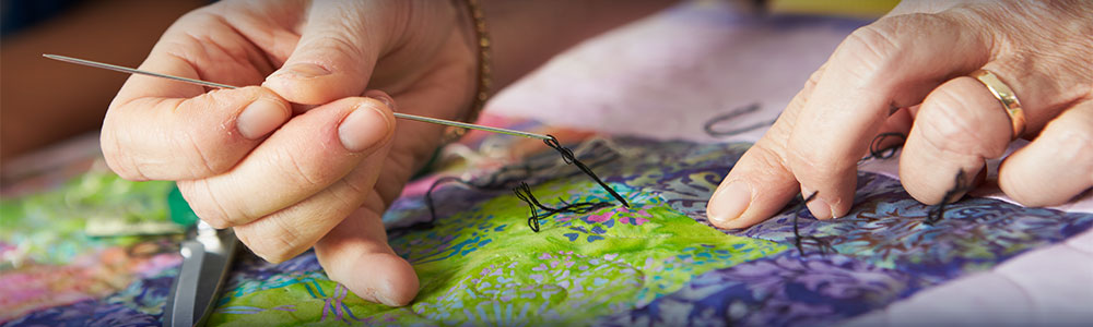 Close Up Of Woman's Hand Sewing Quilt