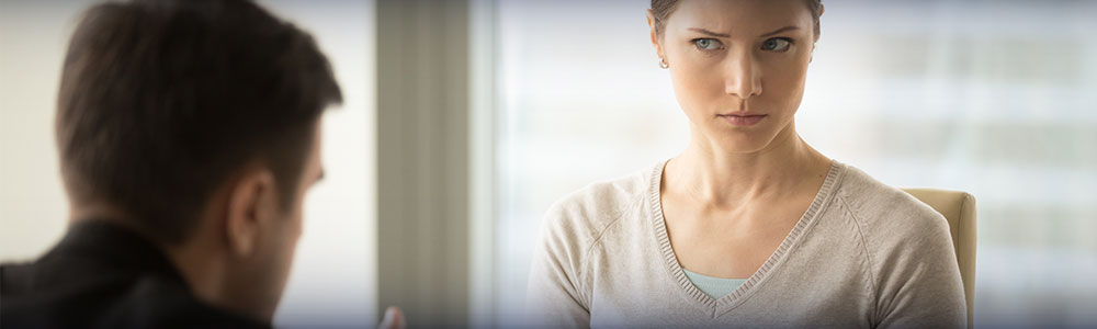 woman looking skeptical at man offering her a sheet of paper.