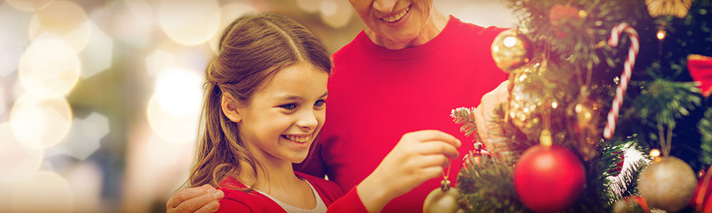 grandmother and granddaughter placing ornaments on a Christmas tree