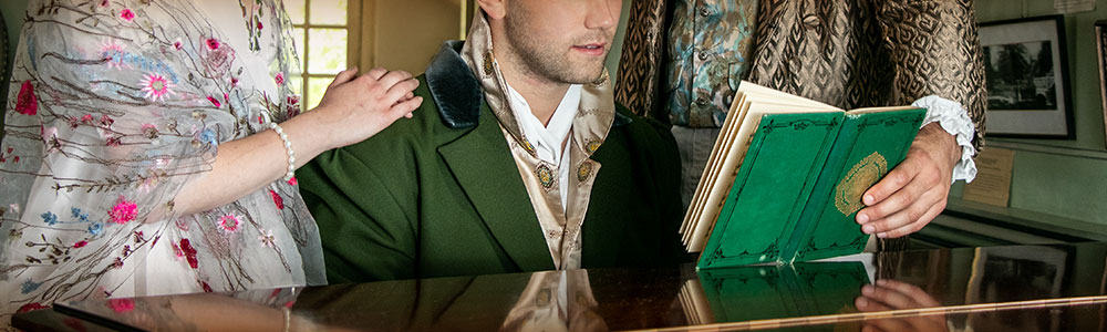 Trio of people in period costume playing piano