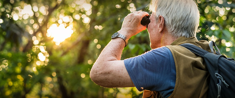 Man with backpack looking through binoculars. 