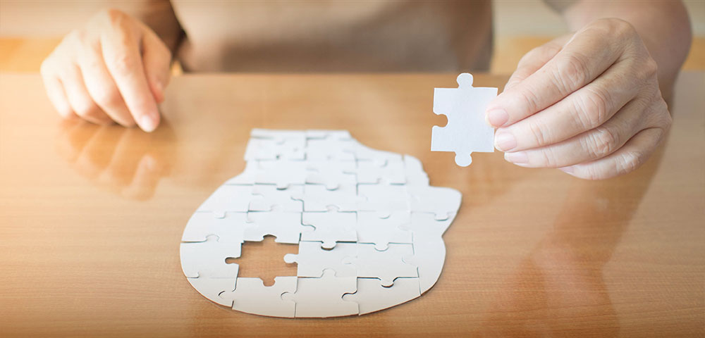 Overhead view of person solving a jigsaw puzzle shaped like a human head.
