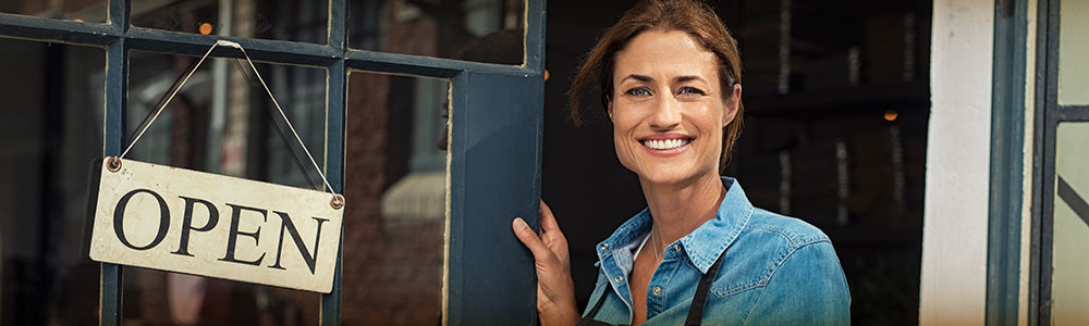  Woman at door of her business with open sign.