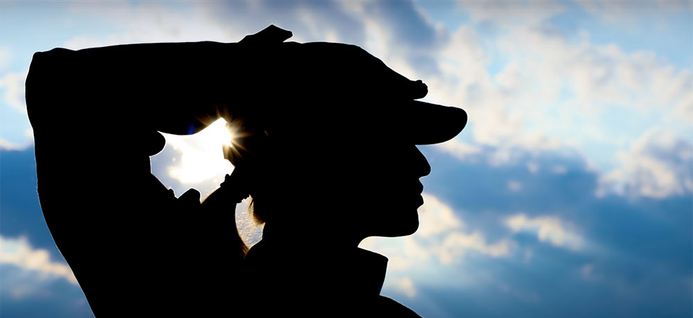  Silhouette of woman in military uniform saluting.