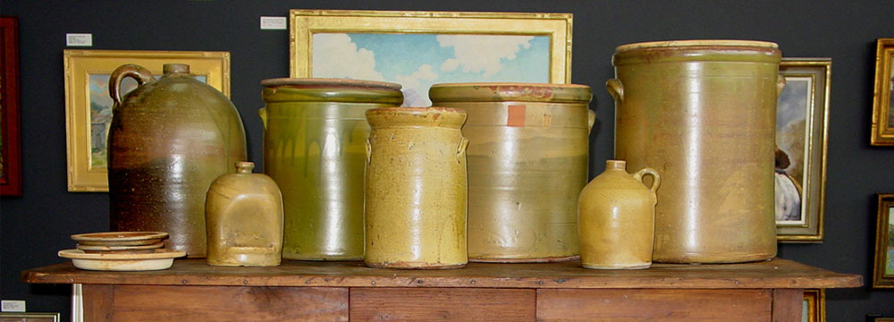 row of pots on table, wall of framed art on back wall