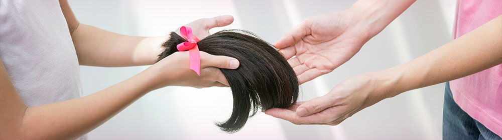 lock of hair tied with pink ribbon handed to another