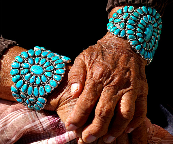 Navajo grandmother showing her turquoise bracelets.