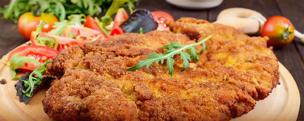 a plate of schnitzel with tomato salad