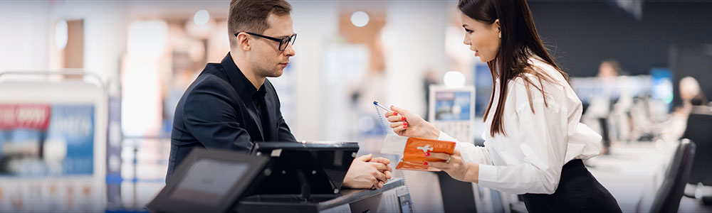 airline passenger speaking with attendant at ticket counter