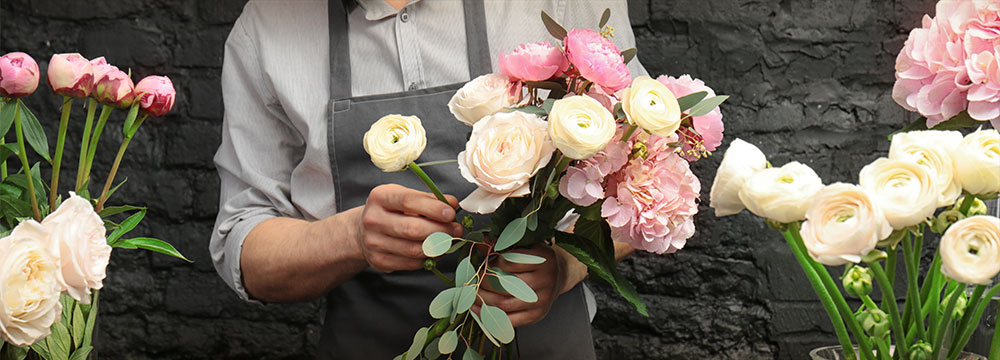 Person in apron making bouquets.
