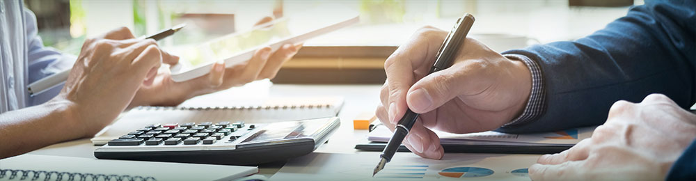 Closeup of hands at desk with tablet, calculator and financial documents