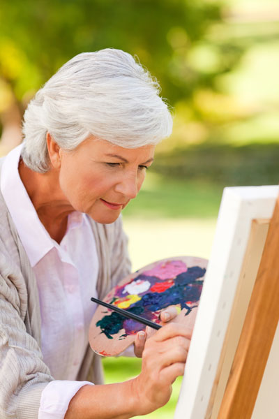 woman painting on a stretched canvas outside
