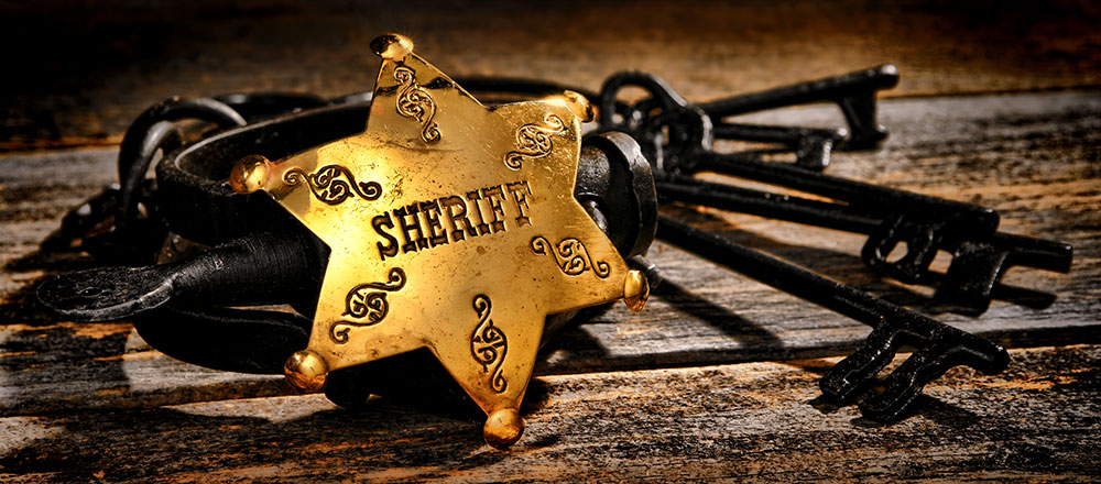 sheriff badge and iron keys on wooden table