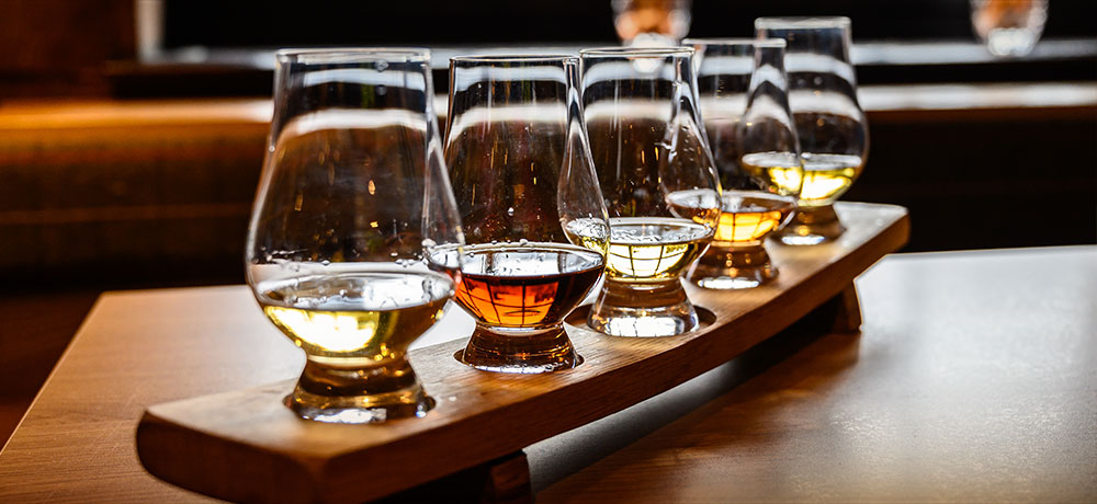 row of glasses with different whiskeys