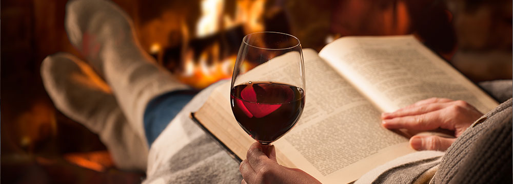  reading in front of a fire with a glass of wine