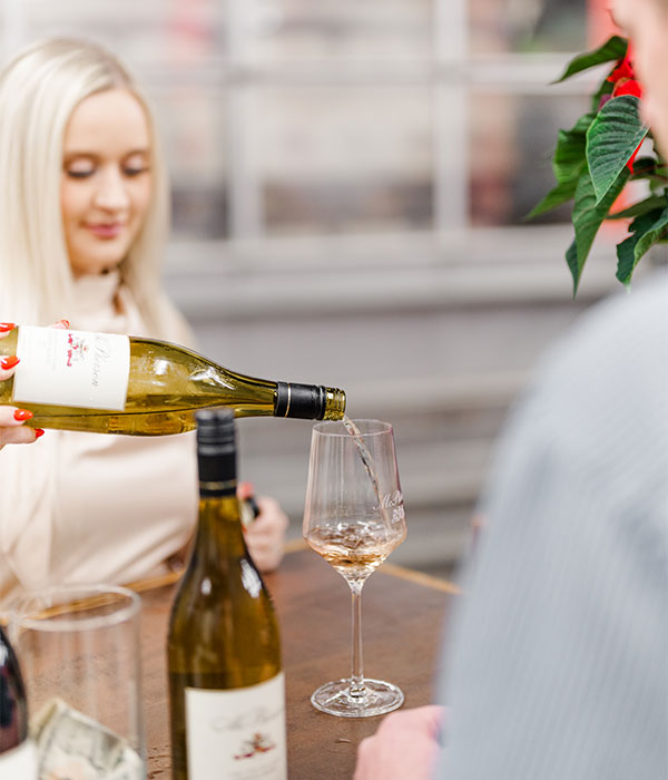 Woman pours wine into glass for tasting.