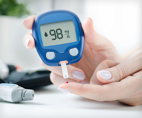 Woman using lancelet and glucometer to check blood sugar level.