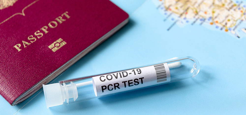 closeup of passport and COVID-19 PCR test over map.
