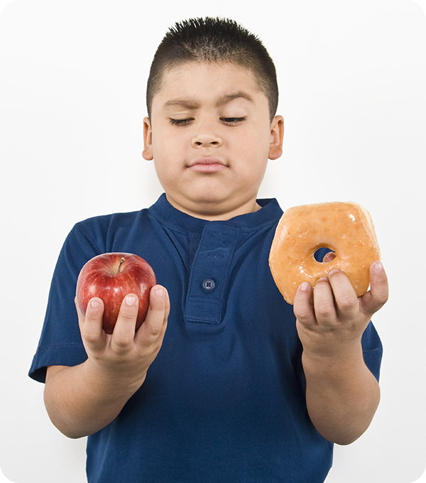 Child holds an apple and doughnut in either hand mentally weighing which snack to eat.
