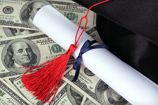 Diploma and mortarboard on bed of hundred dollar bills