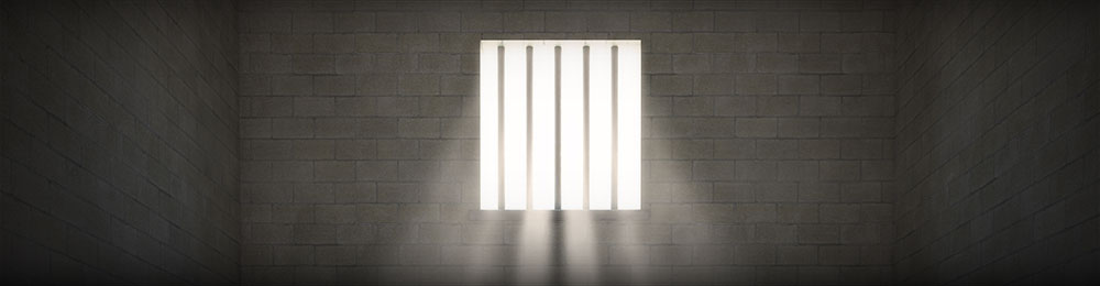 Light shines through barred window in prison cell.