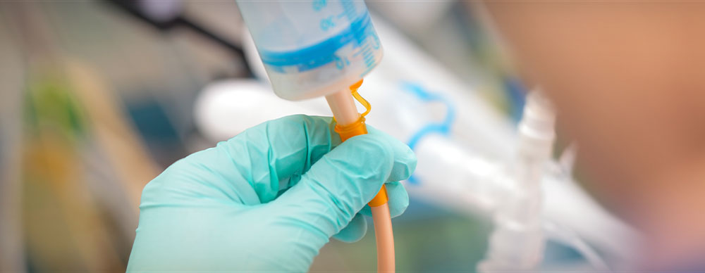  Gloved hands loading a feeding tube. 