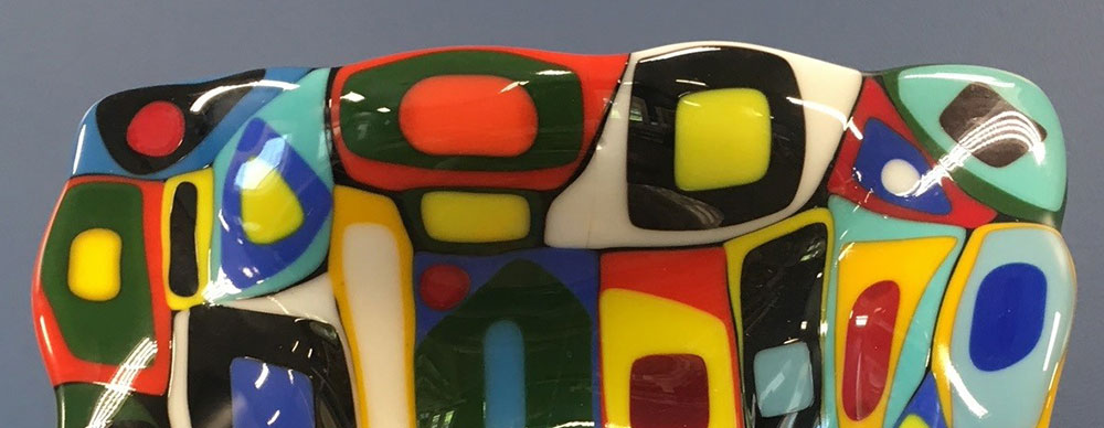Bowl decorated with colorful abstract design created with fused glass.