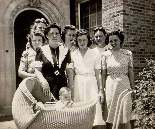 Group of women with a child in bassinet in front of the Home Management House.