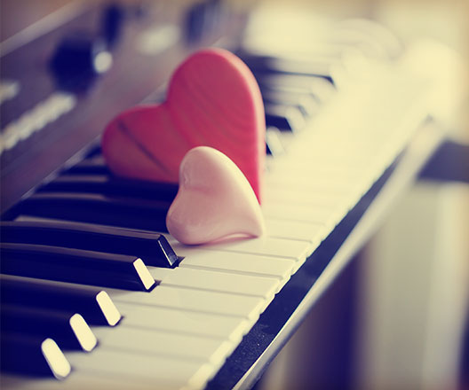 Pink and red wooden hearts on piano keys.