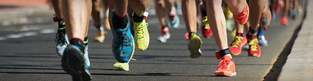 Close up of marathoners' lower legs running on a city road.